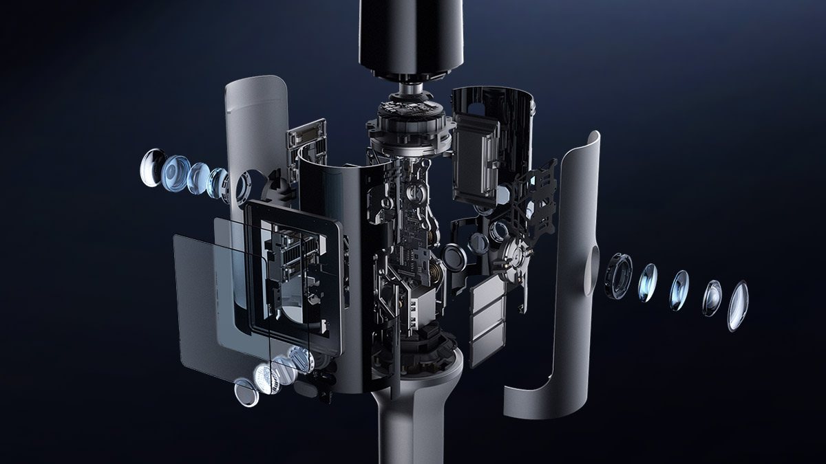 Exploded render of the Kosmo One sensor head: curved grey housing panels pulled away, lens stacks for two opposed fisheye cameras floating left and right, circuit boards and a display panel in the middle, and a black cylindrical module above the core.